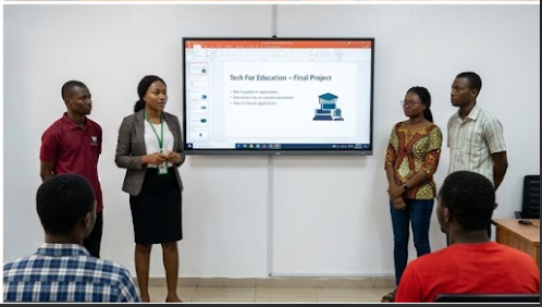 A group of four individuals presenting a project in front of a large screen displaying 'Tech For Education - Final Project' in a classroom setting.