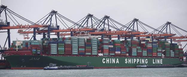 A large cargo ship marked with 'CHINA SHIPPING LINE' docked at a port, loaded with colorful shipping containers, with cranes in the background.