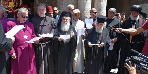 A group of religious leaders of different denominations gathered outdoors, participating in a ceremony while holding sheets of paper and wearing distinctive religious attire.