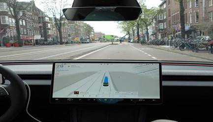 Interior view from the driver's seat of a car showing a large digital display with navigation directions, displaying a street scene ahead.