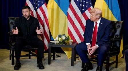 Ukrainian President Volodymyr Zelensky speaking during a meeting with former US President Donald Trump, with flags of the USA and Ukraine in the background.